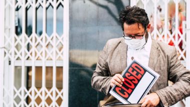 Business man holding closed sign due to covid