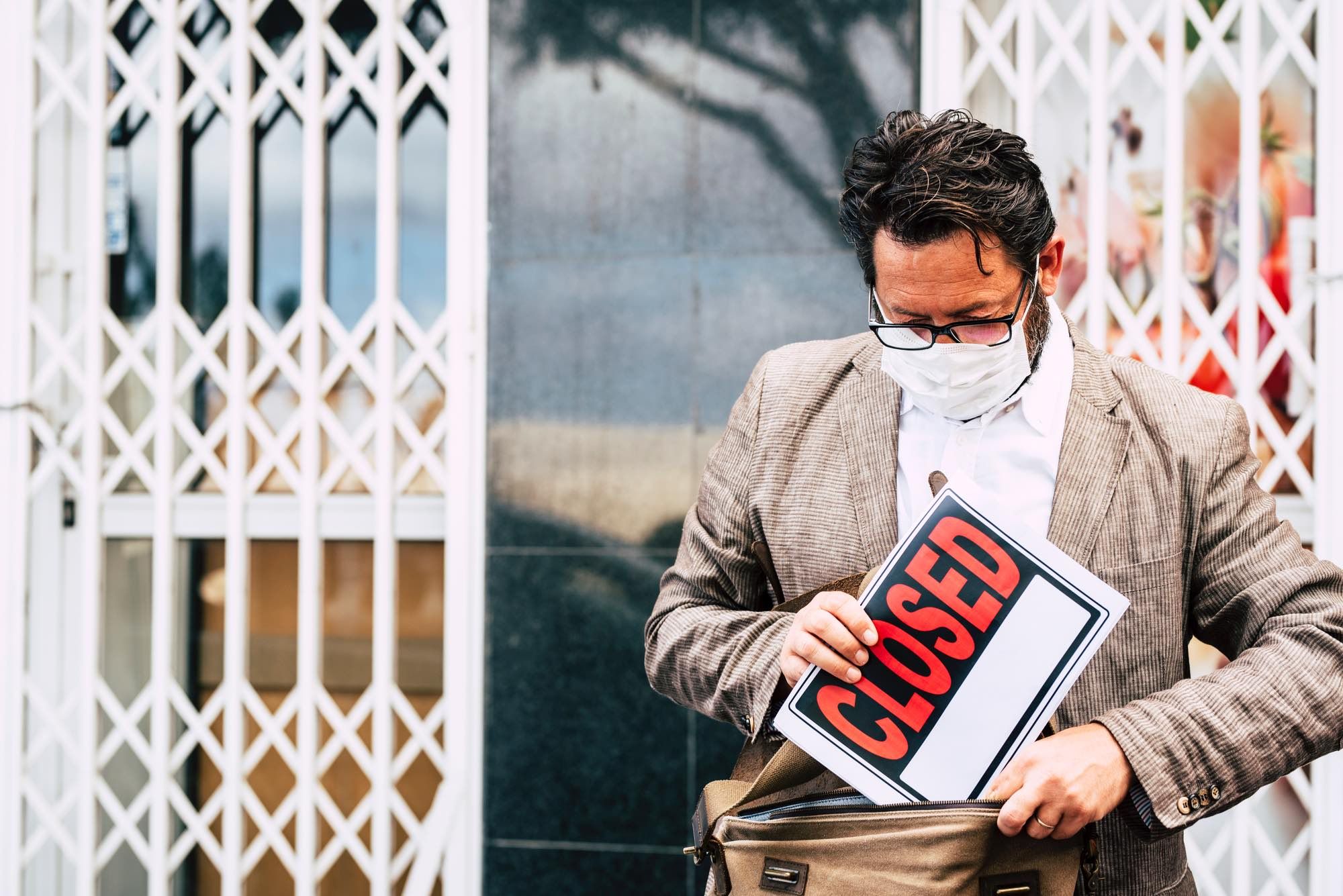 Business man holding closed sign due to covid