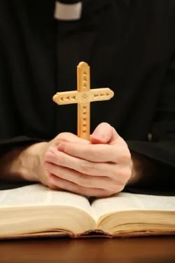 Priest holding wooden cross amid sexual abuse claims