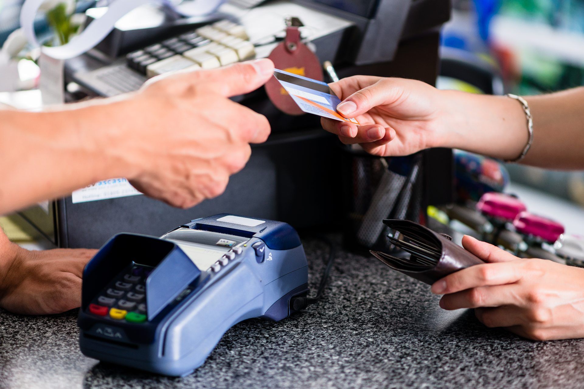 A woman hands her debit or credit card to a cashier - NSF fee