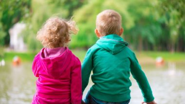 A girl and boy sit on a bench by a lake - crown wards