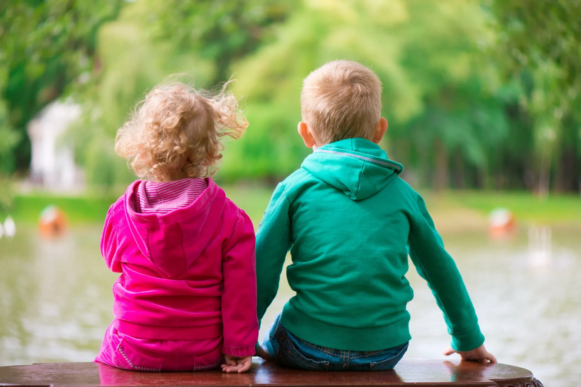 A girl and boy sit on a bench by a lake - crown wards