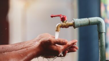 The hand is supporting the water from the tap. Choose focus on the faucet