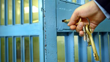 Police officers locks the door in prison corridor.