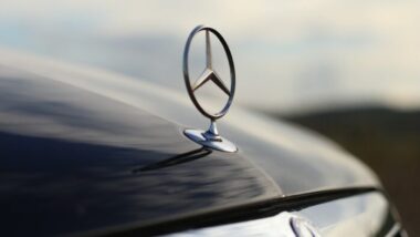 Close up of Mercedes emblem against a cloudy sky.