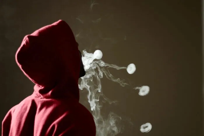 Young male in red hoodie vaping smoking.