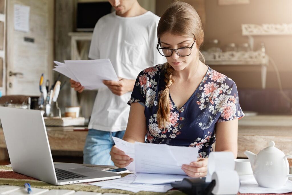Couple anaylzing physical copies of mortgage statements, representing the CIBC mortgage prepayment class action settlement.
