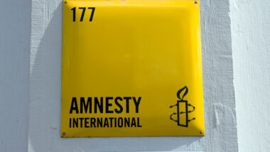 Close up of Amnesty International signage against a white wall.
