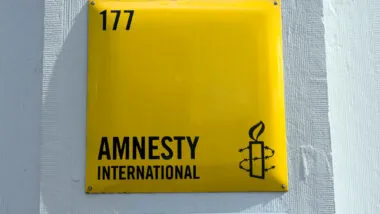 Close up of Amnesty International signage against a white wall.