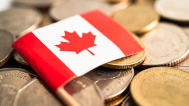 Mini Canadian flag resting on top of coins.