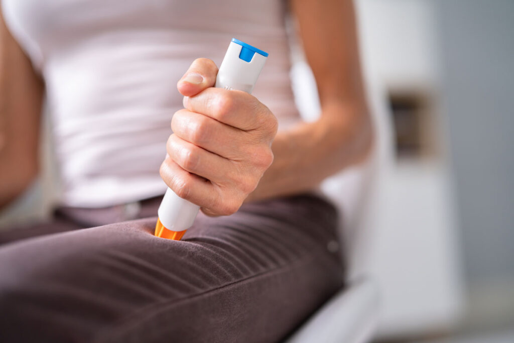 Close up of a woman using an epinephrine auto injector.