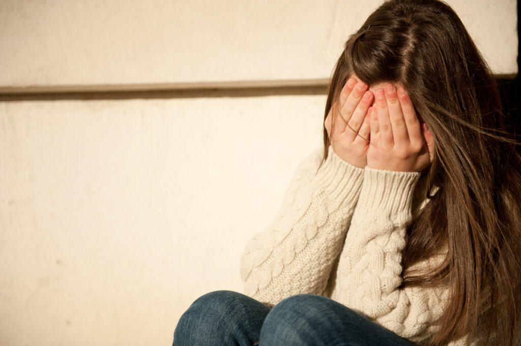 Young Girl Covering Her Face With Her Hands.