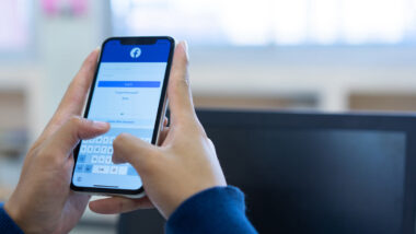 Close up of hands holding a smartphone logging into Facebook, Representing Canada’s Online News Act.