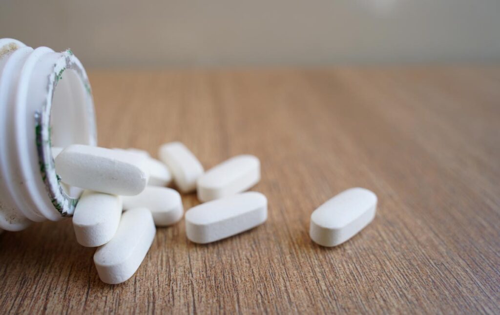 Close up of white pills spilling out of a pill bottle, representing the OxyContin settlement.