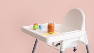 Baby highchair with food on color background representing the TOMY high chair recall.