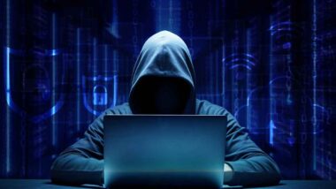 A hooded hacker using a computer, representing the hacker arrest.