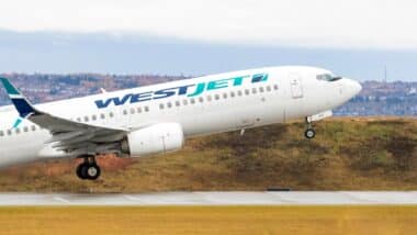 A WestJet plane taking off a runway, representing the WestJet baggage fee settlement.