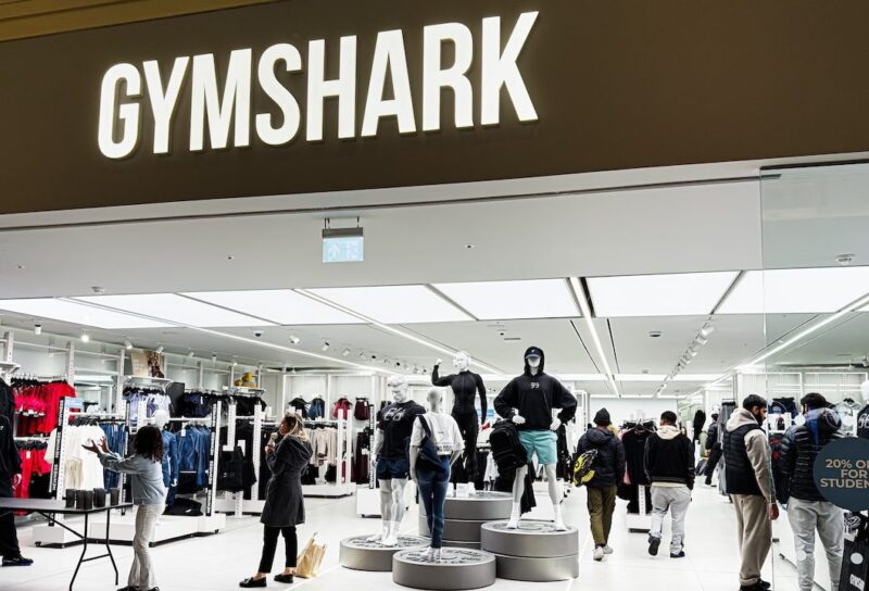 Inside the Gymshark shop, shoppers browse athleticwear around mannequins and bright lighting.